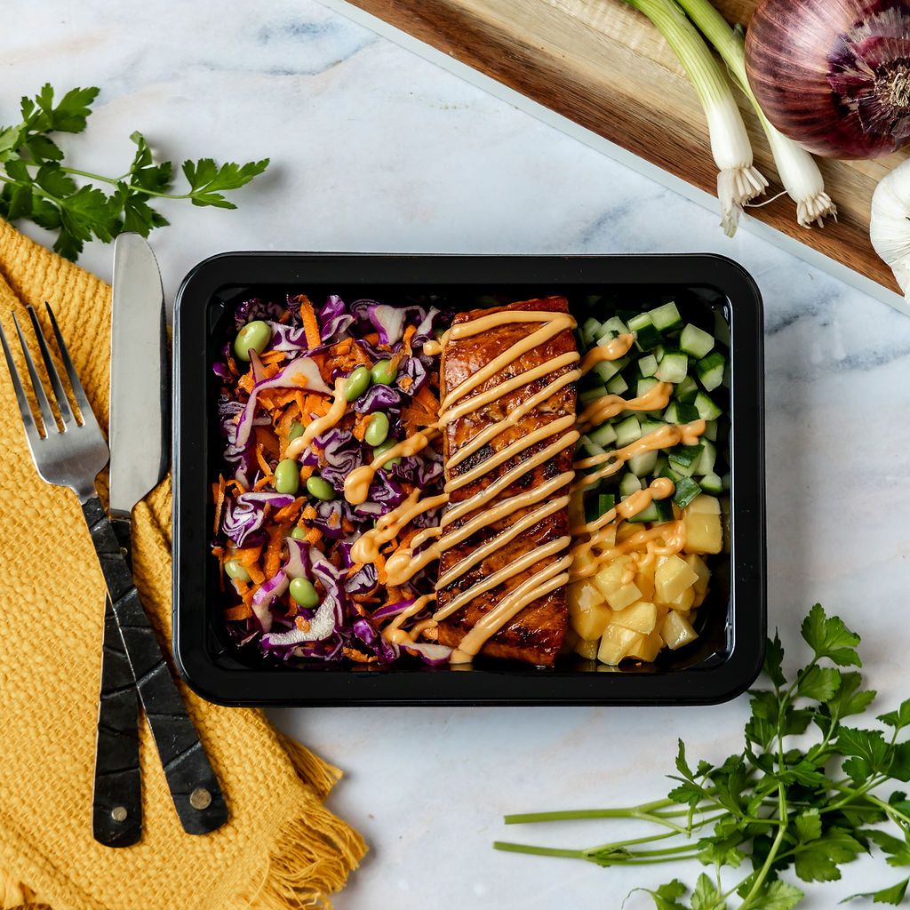 Sushi Bowl - Savory-sweet soy honey sriracha salmon served with crunchy cabbage, edamame, carrots, juicy mango, and crisp cucumber, finished with a…